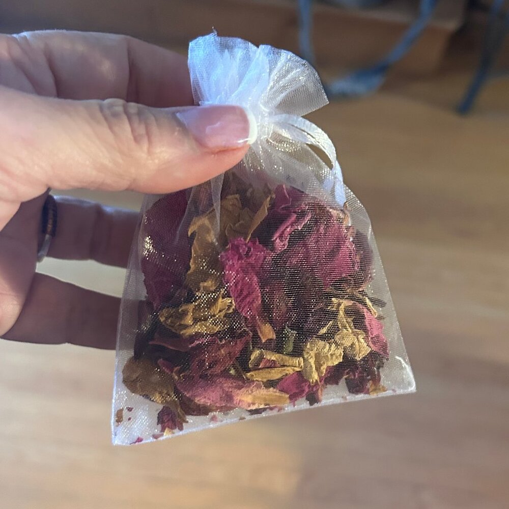 approx 75 small white organza drawstring bags with dried flower petals